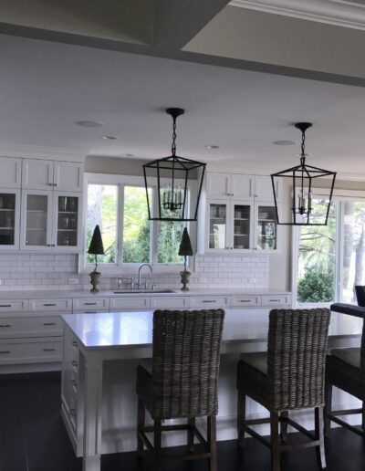 A modern kitchen with white cabinetry, subway tile backsplash, and a central island with pendant lighting.