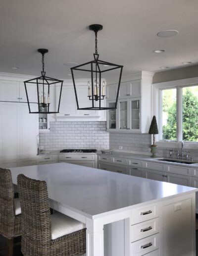 A modern kitchen with white cabinetry, stainless steel appliances, and pendant lighting over a central island.