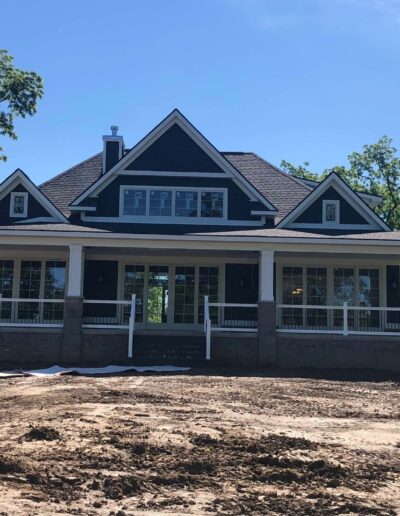 Newly constructed house with a large front porch and blue sky in the background.
