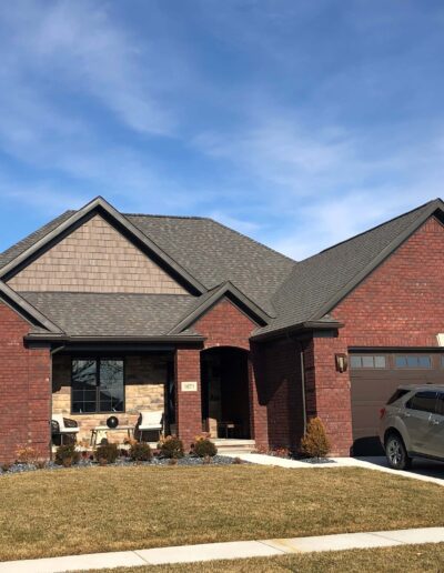 Suburban single-story brick house with an attached two-car garage and a sedan parked in the driveway.