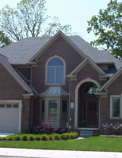 A two-story brick house with an attached garage, arched windows, and a landscaped front yard.