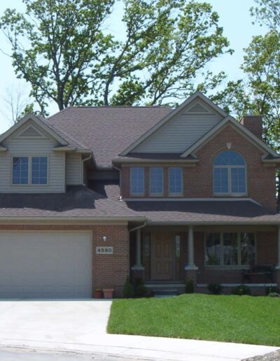 A two-story suburban house with a brick facade, attached two-car garage, and a neatly manicured lawn.