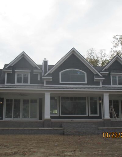Newly constructed two-story house with a gray exterior and large front porch.