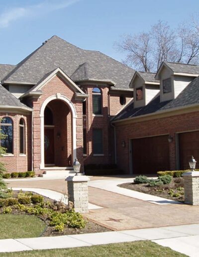 Large brick house with arched entrance and multiple roof peaks.