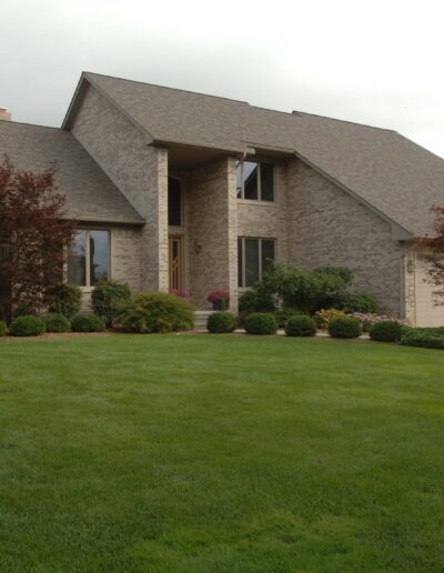A two-story brick house with a well-maintained lawn on an overcast day.