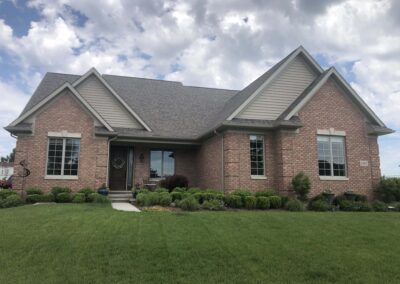 Single-story brick house with gabled roofs and a manicured front lawn.
