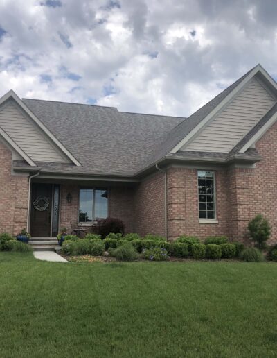 Single-story brick house with gabled roofs and a manicured front lawn.