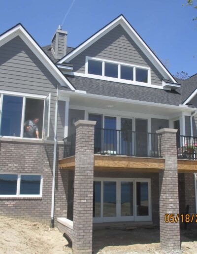 A new two-story house with a brick and siding exterior under construction on a sunny day.
