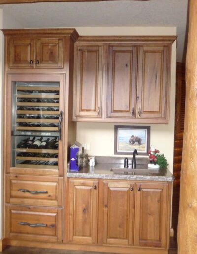 Kitchen cabinetry featuring a built-in wine rack and sink, with warm wooden finishes and a framed picture above the countertop.